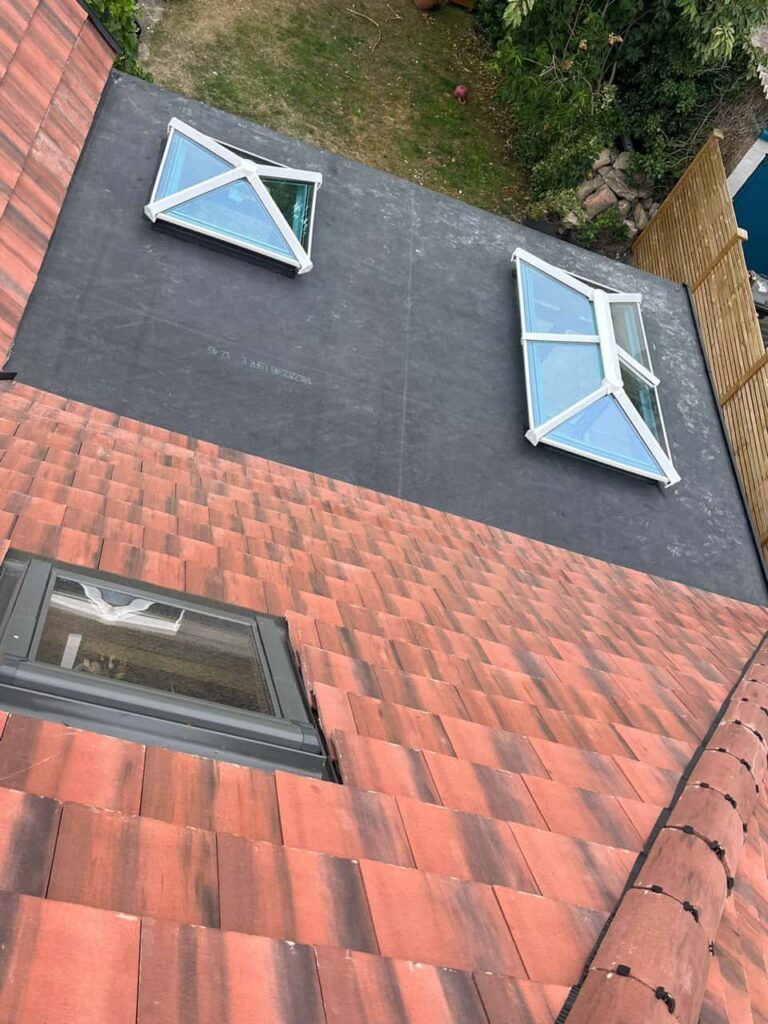This is a photo taken from the roof ridge looking down a tiled pitched roof on to a flat roof. Works carried out by Waterlooville Roofing Repairs